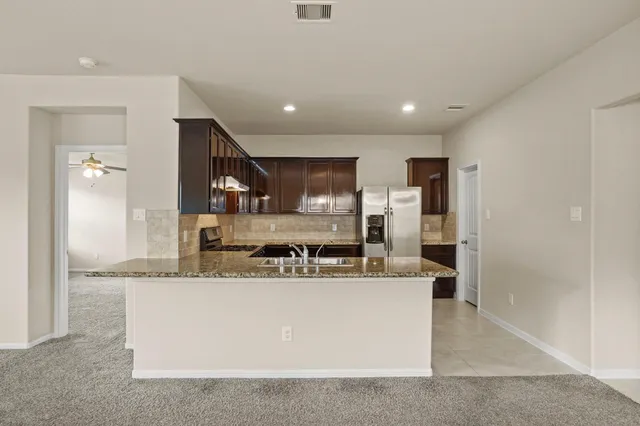 a large kitchen with kitchen island a large counter top stainless steel appliances and cabinets