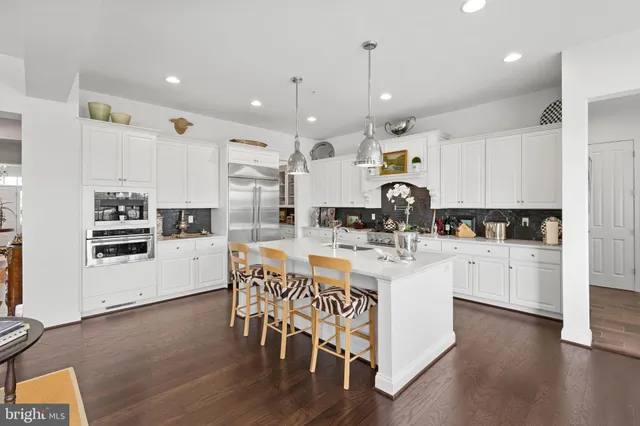 a kitchen with stainless steel appliances kitchen island granite countertop a table chairs and a refrigerator