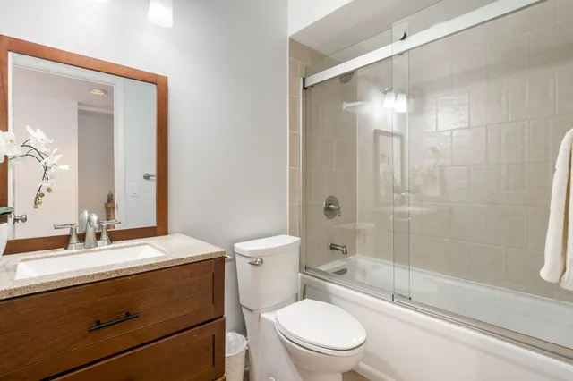 a bathroom with a granite countertop toilet a sink and a mirror