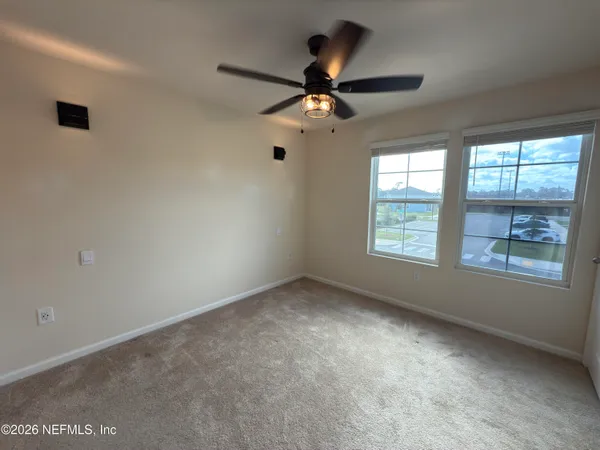en empty room with windows and ceiling fan