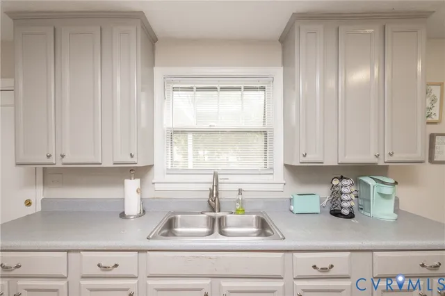 a kitchen with granite countertop white cabinets and window