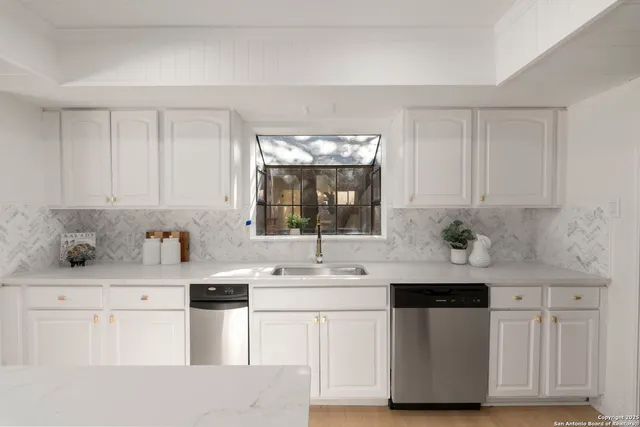 a kitchen with stainless steel appliances granite countertop a sink and a white cabinets