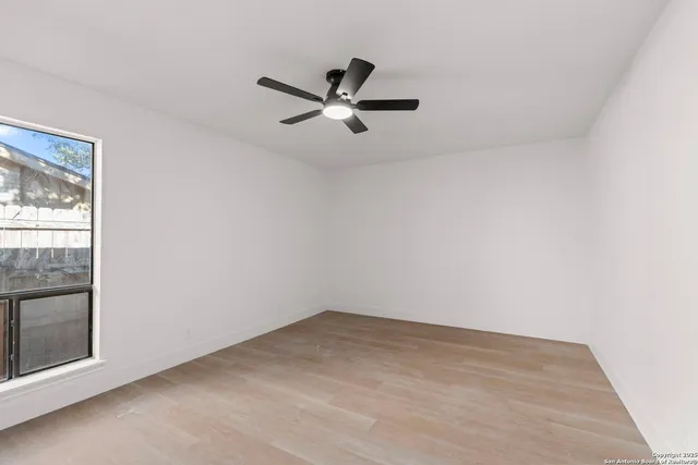 an empty room with a ceiling fan and window
