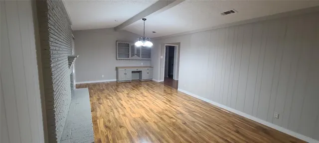 a view of an empty room with wooden floor fireplace and a window