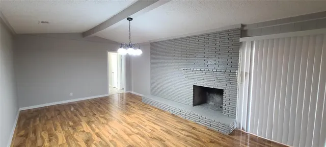 a view of empty room with window and wooden floor