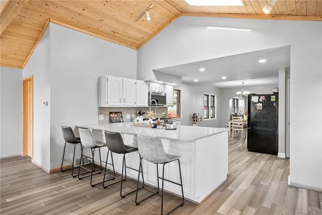 a living room with stainless steel appliances kitchen island a table and chairs in it