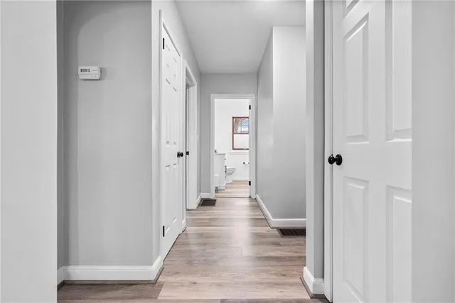 a view of a hallway with wooden floor and closet area