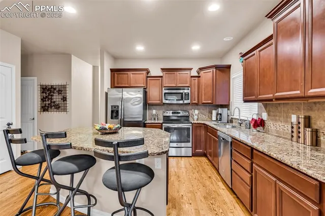 a kitchen with stainless steel appliances granite countertop a stove top oven a sink dishwasher and cabinets with wooden floor