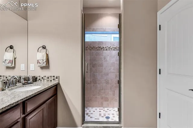 a bathroom with a granite countertop sink a mirror and shower