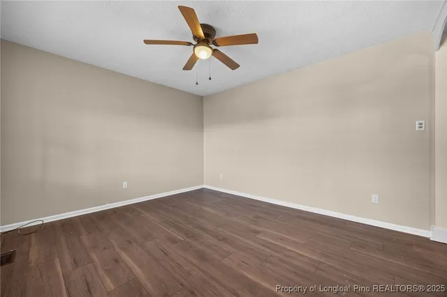 an empty room with wooden floor and a ceiling fan