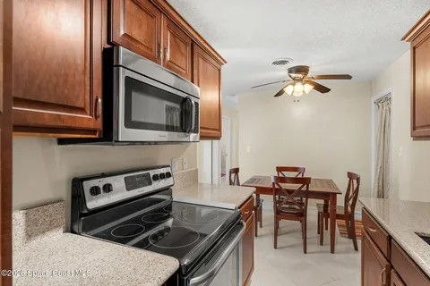 a kitchen with stainless steel appliances granite countertop a sink dishwasher a stove a refrigerator with a dining table and chairs with wooden floor