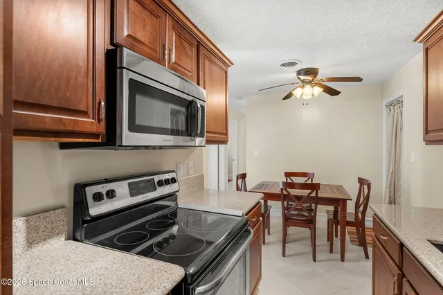 a kitchen with stainless steel appliances granite countertop a sink dishwasher a stove a refrigerator with a dining table and chairs with wooden floor