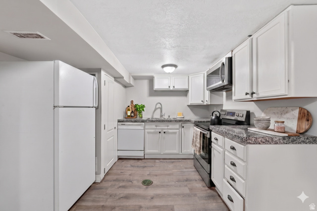 7879 Oak Street Midvale, UT 84047 - Photo 20 of 32 Kitchen featuring wood-finish flooring, white cabinetry with dark hardware, speckled countertops, and a full suite of white and stainless steel appliances