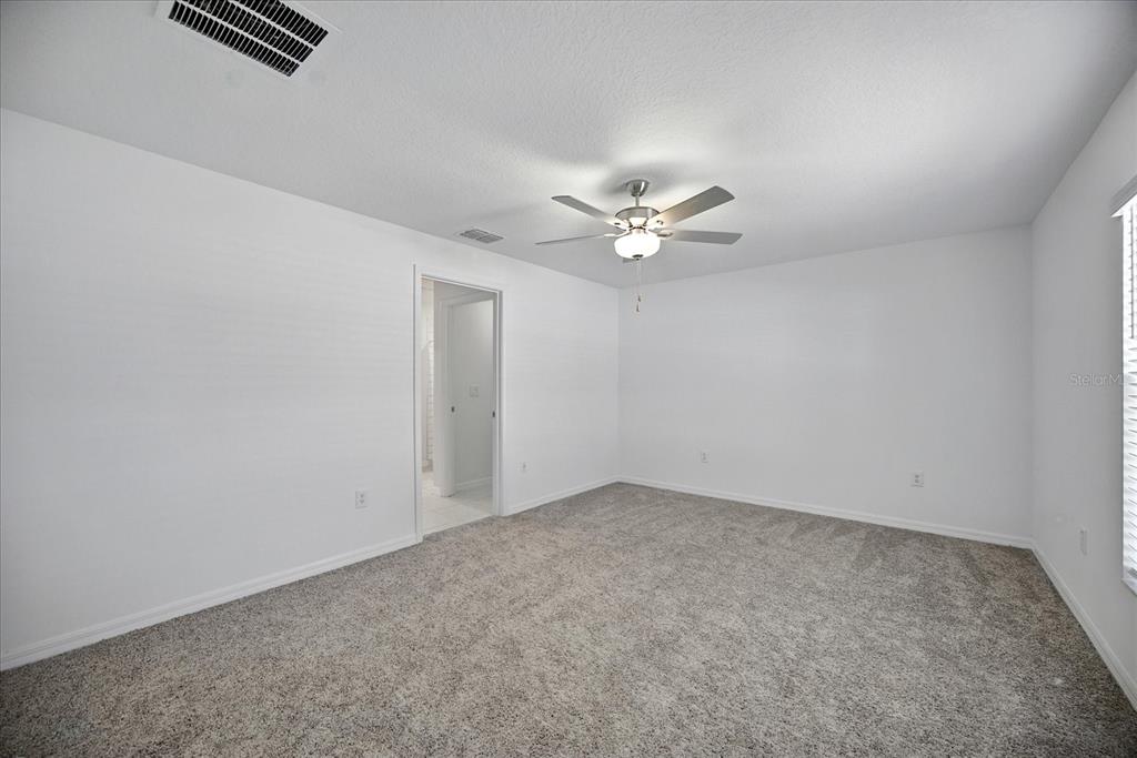 73 Rain Lily Ave Spring Hill Spring Hill, FL 34609 - Photo 15 of 37 an empty room with a chandelier fan and windows
