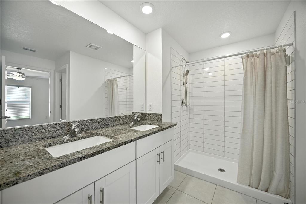 73 Rain Lily Ave Spring Hill Spring Hill, FL 34609 - Photo 20 of 37 a bathroom with a granite countertop sink mirror and shower