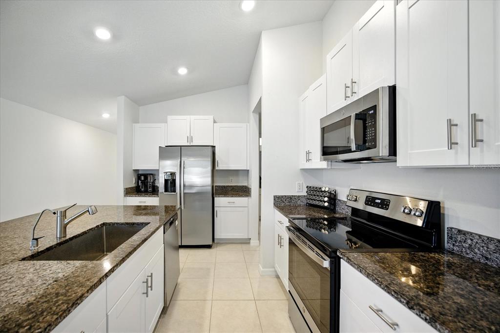73 Rain Lily Ave Spring Hill Spring Hill, FL 34609 - Photo 9 of 37 a kitchen with stainless steel appliances granite countertop a sink stove microwave and refrigerator