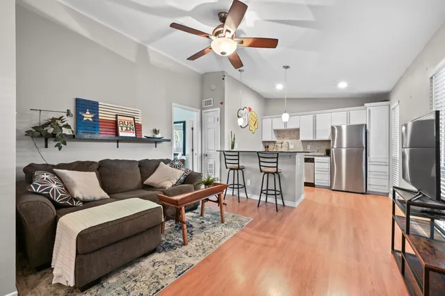 a living room with stainless steel appliances kitchen island granite countertop furniture and a flat screen tv