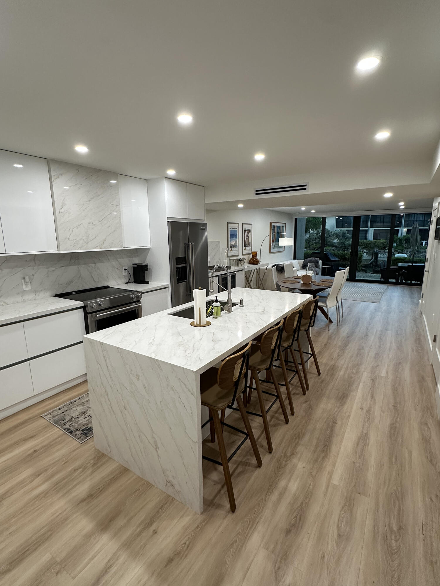 96000 Overseas Highway, Unit C7 Key Largo, FL 33037 - Photo 2 of 14 a kitchen with stainless steel appliances kitchen island granite countertop a stove a refrigerator a sink a dining table and chairs with wooden floor