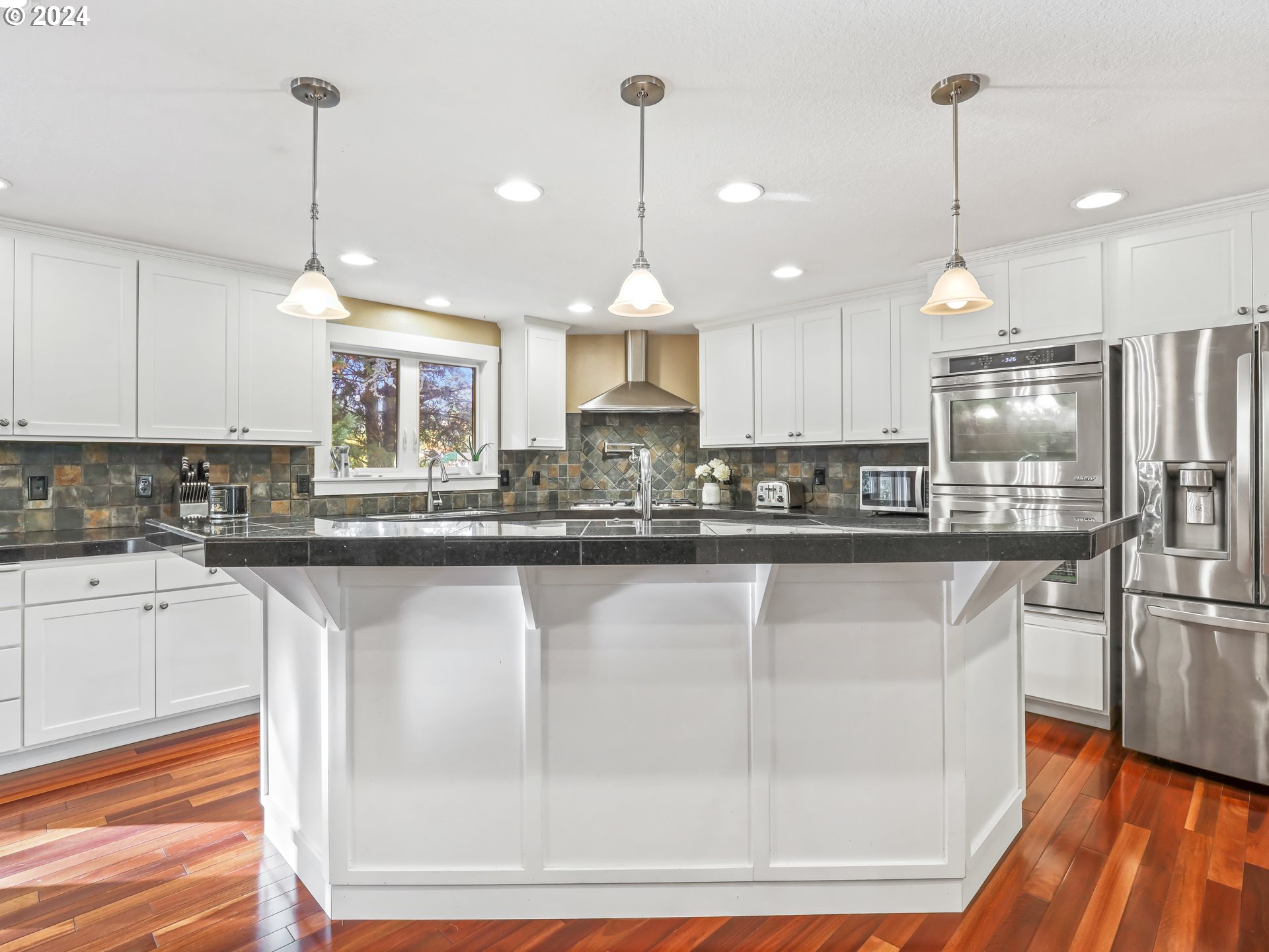 16787 Southeast Tong Road Damascus, OR 97089 - Photo 12 of 47 a kitchen with kitchen island granite countertop a stove a sink a center island a refrigerator and wooden floor