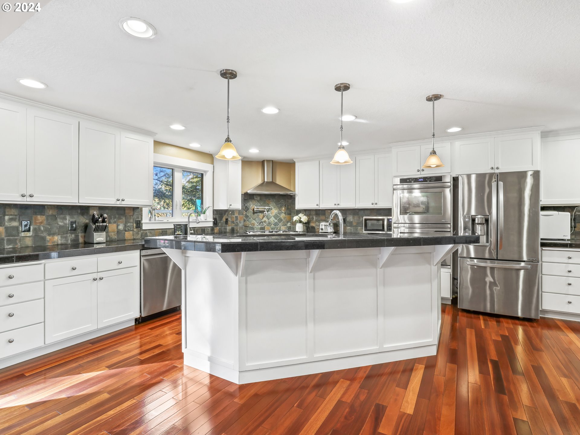 16787 Southeast Tong Road Damascus, OR 97089 - Photo 13 of 47 a kitchen with stainless steel appliances granite countertop a refrigerator a sink dishwasher a stove and white countertops with wooden floor
