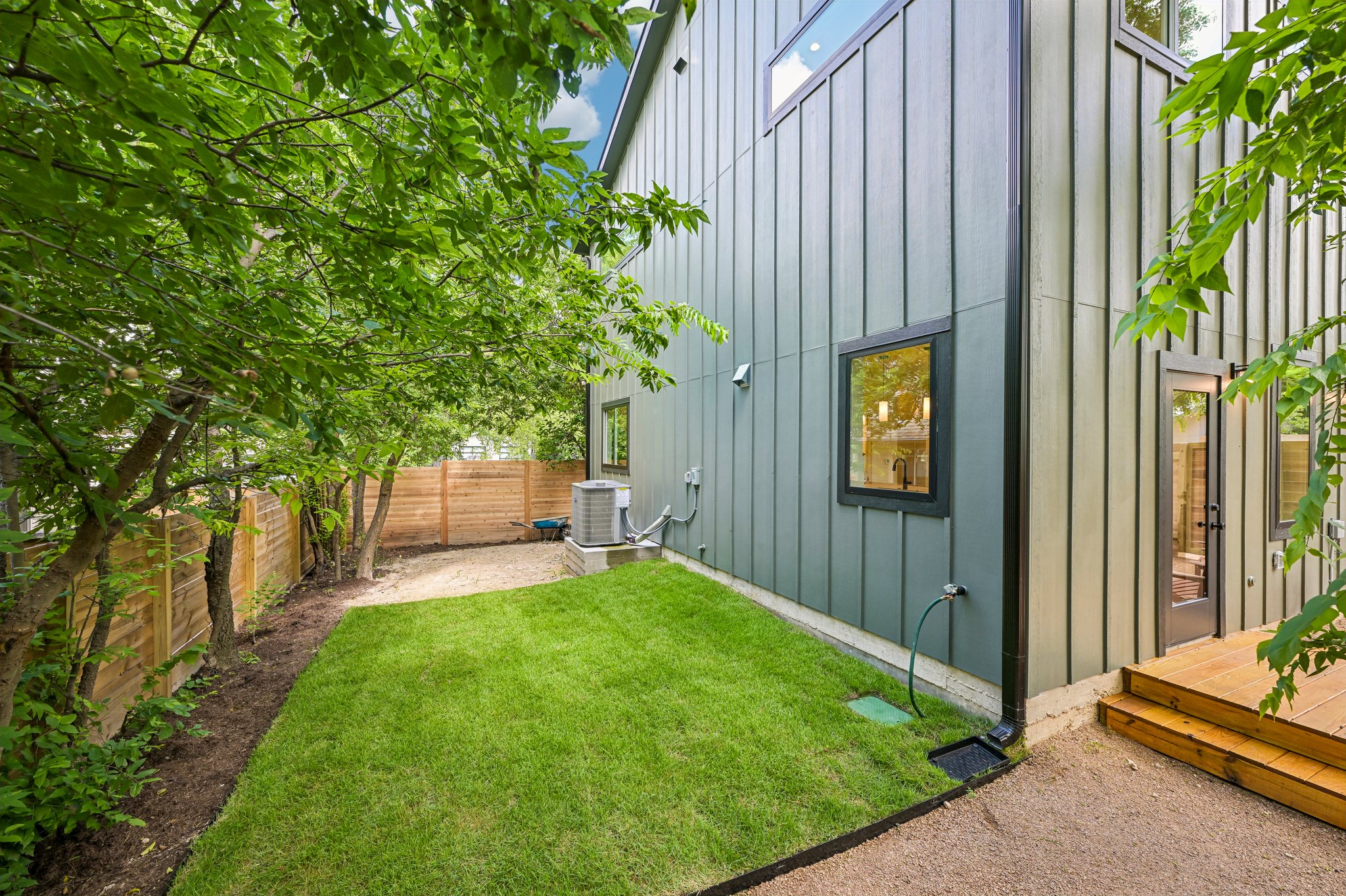 513 West Odell Street, Unit B Austin, TX 78752 - Photo 33 of 38 Green landscaping and a wooden privacy fence frame this modern home's exterior.