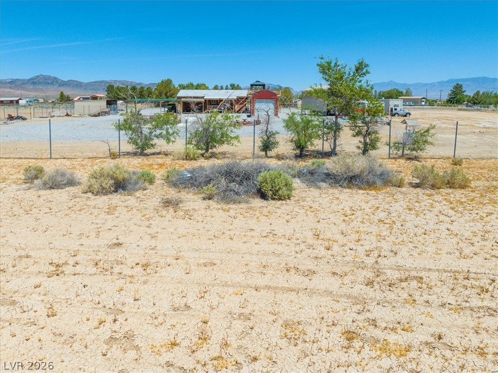 4580 Lawrence Road Pahrump, NV 89048 - Photo 16 of 40 A spacious, arid lot offers expansive rural views with a distant structure under an open sky.