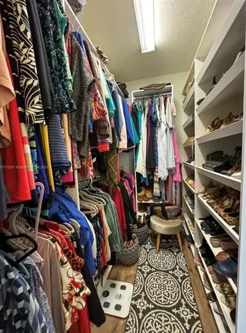 a view of walk in closet with clothes and shoes