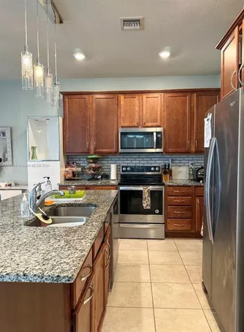 a kitchen with kitchen island granite countertop a stove sink and refrigerator