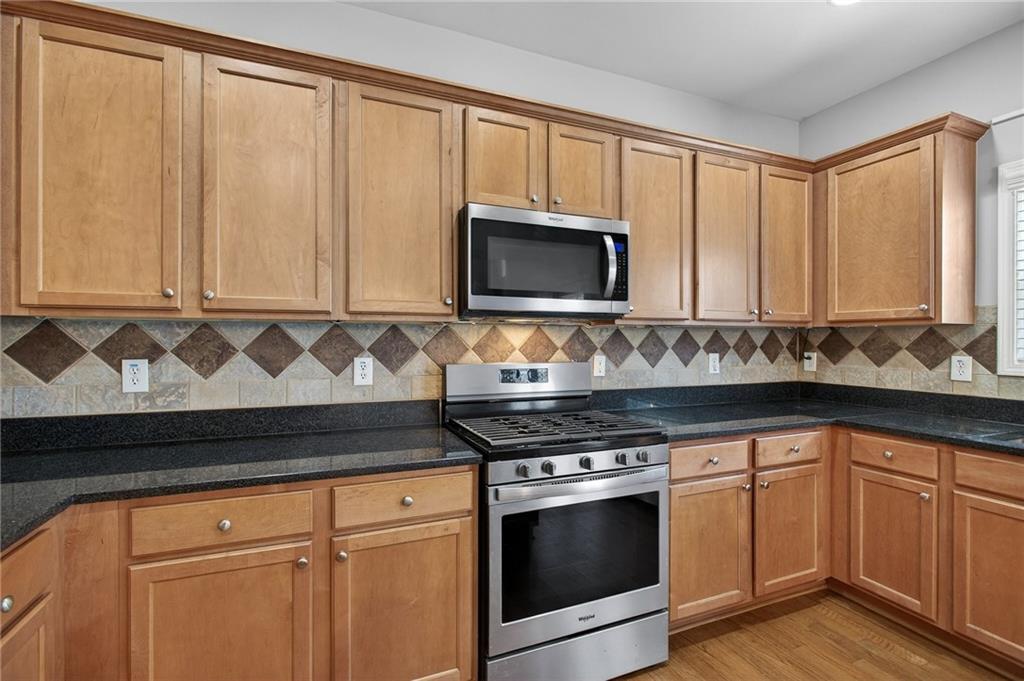 103 Forest Creek Way Canton, GA 30115 - Photo 25 of 55 a kitchen with granite countertop white cabinets and black stove top oven with wooden floor