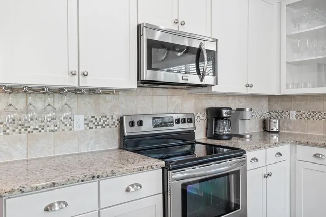 a kitchen with granite countertop a sink and a white wooden cabinets