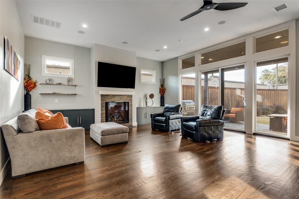7912 Hanover Street Dallas, TX 75225 - Photo 24 of 29 Spacious living area featuring rich wood-finish flooring, a contemporary fireplace with stacked stone surround, and extensive glass sliding doors