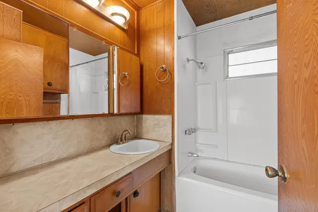 a bathroom with a granite countertop sink mirror and a bathtub