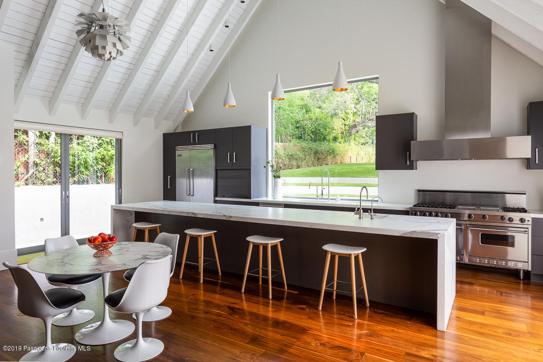 561 Woodland Road Pasadena, CA 91106 - Photo 12 of 41 a kitchen with stainless steel appliances granite countertop a stove a refrigerator a dining table and chairs with wooden floor