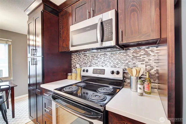 a kitchen with granite countertop a stove top oven cabinetry a sink and a window