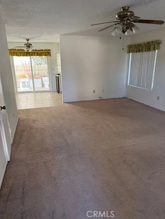 an empty room with windows and chandelier fan