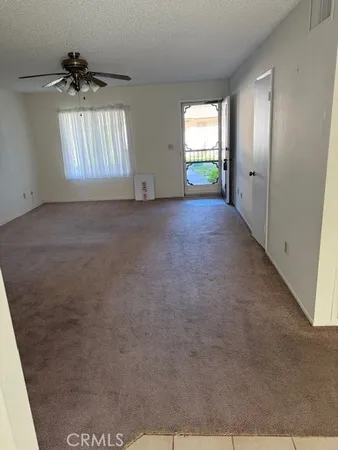 an empty room with windows and chandelier fan