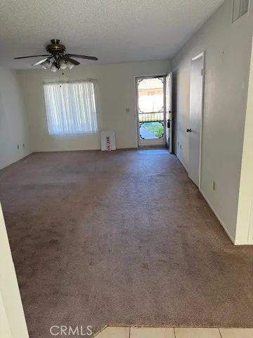 an empty room with windows and chandelier fan