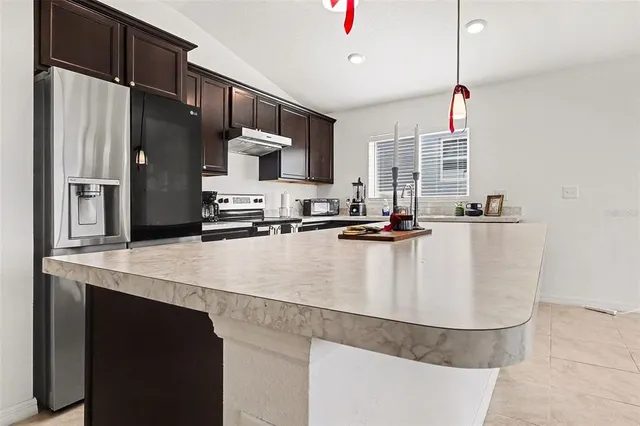 a kitchen with kitchen island stainless steel appliances a sink stove and refrigerator