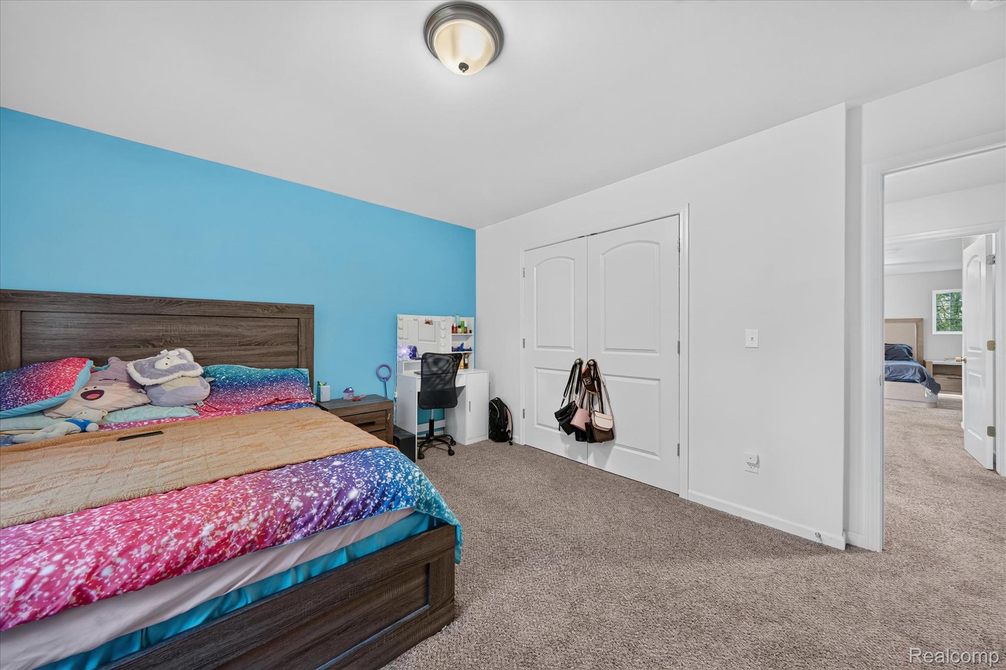 5382 Rural Terrace Waterford, MI 48329 - Photo 23 of 35 Spacious bedroom featuring a vibrant accent wall, wood-finish bed frame, plush carpet flooring, and a double-door closet with arched paneling