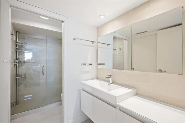 a bathroom with a sink shower and a mirror