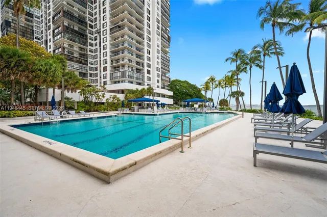 a view of a swimming pool with a lawn chairs and palm trees