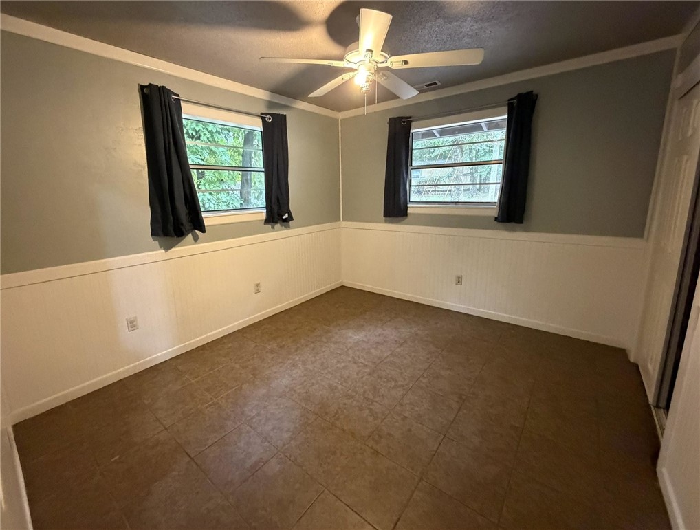 5108 Ridge Road Alma, AR 72921 - Photo 17 of 33 Room featuring wainscoting, crown molding, two windows, tile flooring, and a ceiling fan