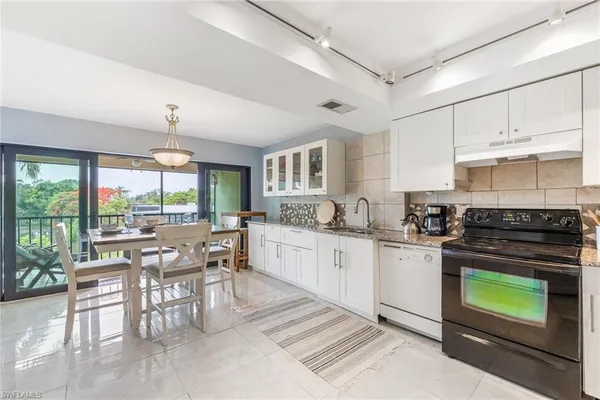 a kitchen with stainless steel appliances granite countertop a stove a sink dishwasher a dining table and chairs with wooden floor