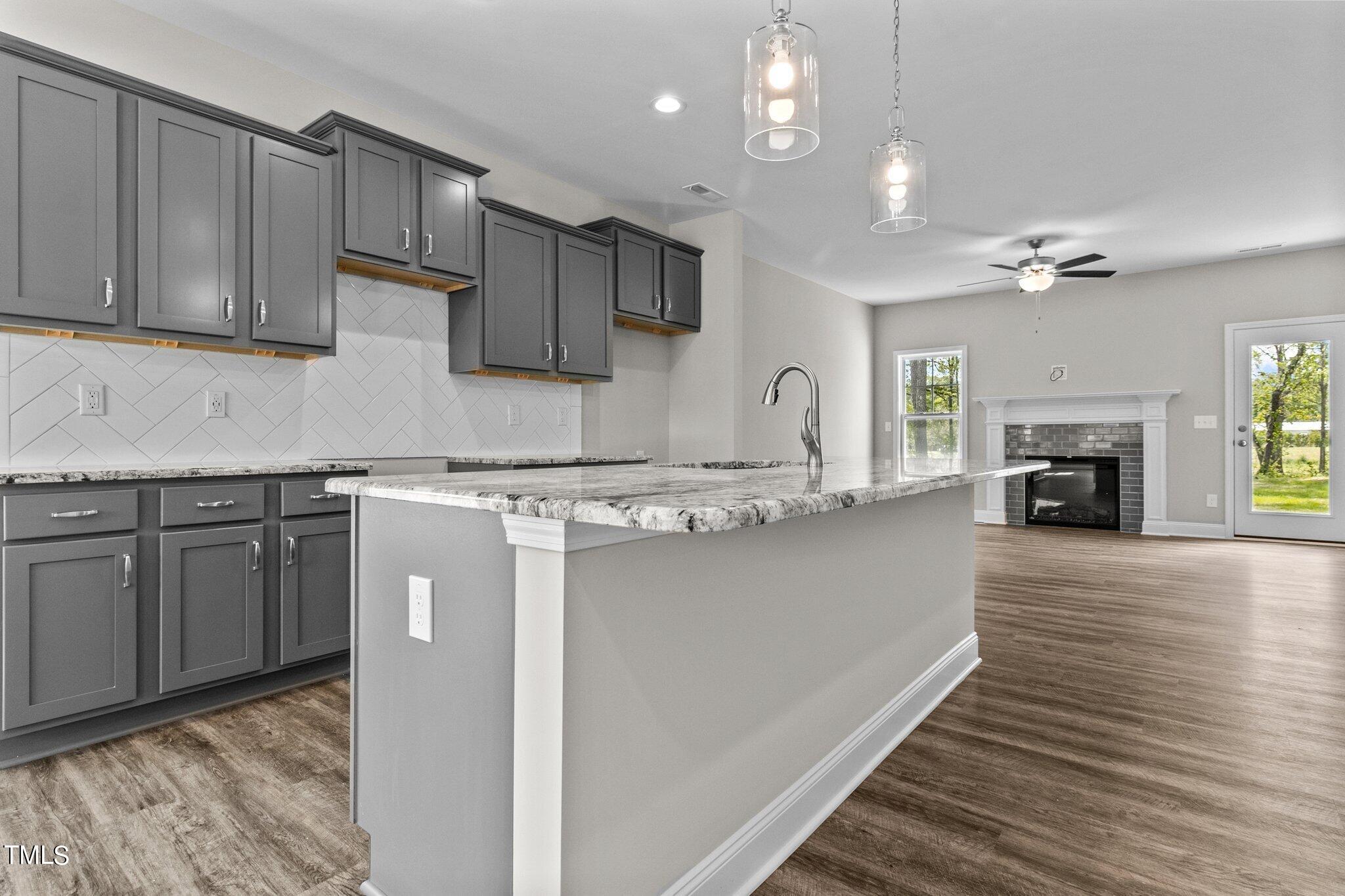111 Regis Lane Coats, NC 27521 - Photo 9 of 36 a kitchen with granite countertop a stove top oven a sink dishwasher and a fireplace with wooden floor