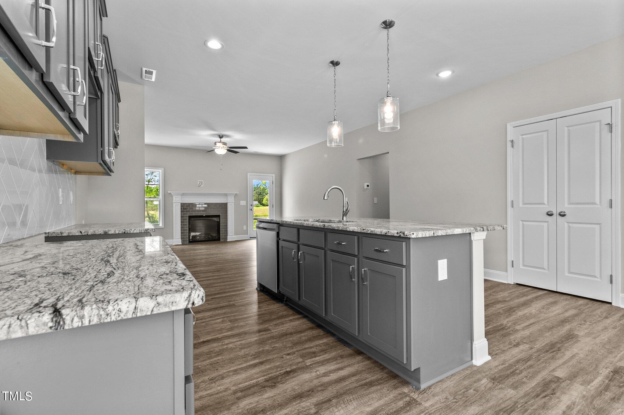 111 Regis Lane Coats, NC 27521 - Photo 10 of 36 a large kitchen with kitchen island a large island wooden floor stainless steel appliances and a fireplace