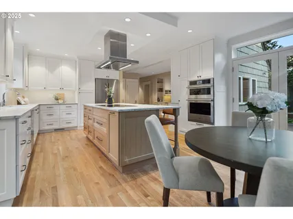a kitchen with stainless steel appliances kitchen island granite countertop a table chairs sink and cabinets