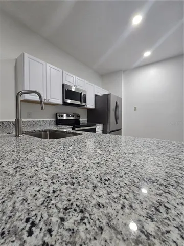 a kitchen with granite countertop a stove a sink and a microwave