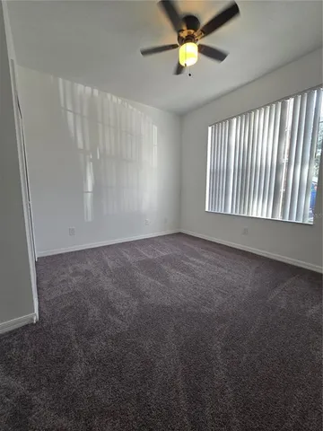an empty room with a window and a ceiling fan