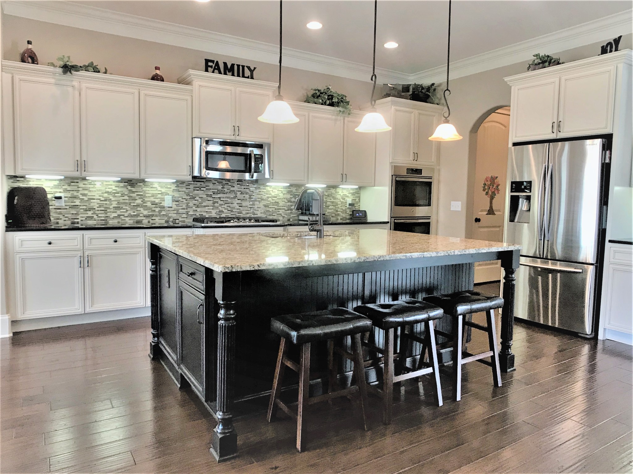 a kitchen with stainless steel appliances granite countertop a table chairs stove and microwave