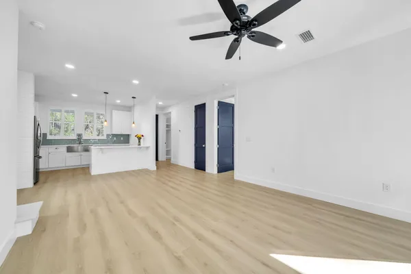 a view of an empty room with kitchen appliances and a ceiling fan